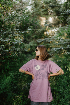 Una mujer con un remerón rosa de la colección Santa Teresa, posando entre la vegetación de la selva.