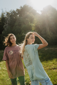 Dos modelos luciendo el remerón Santa Teresa, uno en color lila claro y otro en verde claro, en un entorno natural.