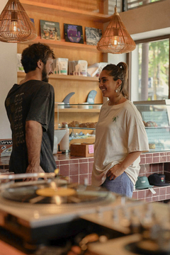 Una pareja conversando en un café, con la mujer vistiendo un remerón claro y sonriendo, mientras el hombre lleva una camiseta oscura.