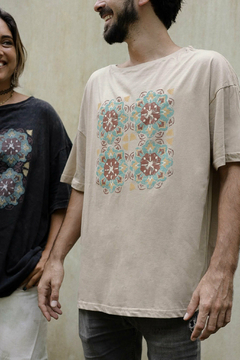 Remerón color beige con estampado de motivos geométricos, usado por un hombre, junto a una mujer con remerón oscuro en un fondo neutro.
