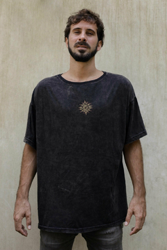 Hombre posando con un remerón negro de la colección 2024, con un diseño bordado en el pecho.