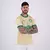 Homem com tatuagens usando a camisa do Palmeiras, de cor bege com detalhes em verde, posando com os braços cruzados.