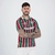 Homem posando com a camisa do Fluminense, apresentando as cores verde, vermelho e branco, com tatuagens visíveis nos braços.