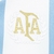 Detalhe do emblema da Camisa Argentina 2025/26 Comemorativa 1974 Adidas Feminina, com a sigla AFA em dourado e elementos decorativos em branco e azul.