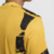 Detalhe das costas da camisa dourada do Inter de Milão, com design gráfico em preto.