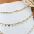 Colar choker com detalhes em gotas, banho de ouro 18k, ajustado ao pescoço.