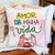 Almofada colorida com a frase 'Amor da Minha Vida' escrita em letras coloridas sobre um fundo degradê de rosa e verde. Abaixo da frase, há uma ilustração de duas mãos fazendo o gesto de coração, com chaves desenhadas flutuando ao redor. O design inclui pe