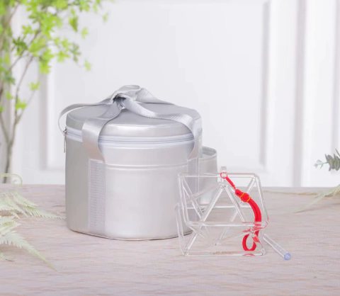 Pirâmide Merkaba Cristal Cantante em uma embalagem prateada, com detalhes em vermelho.