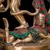 Estátua de Shiva Nataraja em detalhes, mostrando a figura de Shiva dançando e uma de suas consortes em uma pose relaxada, com adornos coloridos.