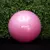 Pelota de esferodinamia rosa de 55 cm con logo "Get Fit!" delante de un fondo de plantas verdes.