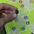 Primer plano de una mano sosteniendo un imán frente a una pizarra táctica magnética de fútbol con fichas de colores.