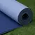 Colchoneta de yoga TPE 6 mm azul enrollada sobre césped