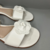 Sandália rasteira flat aplicação de flor e trançada no tornozelo off white - comprar online