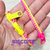 Foto: Pulseira zíper de plástico com uma faixa amarela e outra rosa.