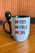 Caneca com as palavras "Foco", "Força" e "Café" em destaque, acompanhada de uma colher preta.