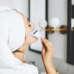 Mulher usando um rolo de gelo de aço inoxidável para skincare no rosto