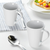 Canecas cônicas de porcelana branca 290ml em uma mesa posta com colher e prato ao fundo