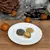 Prato sobremesa de porcelana branca com 20,5 cm contendo três biscoitos decorativos sobre superfície de madeira
