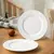 Pratos de sobremesa brancos de porcelana com 20,5 cm sobre mesa de madeira