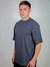 Homem vestindo uma camisa oversized PIMA na cor chumbo, de manga curta, posando em fundo neutro.