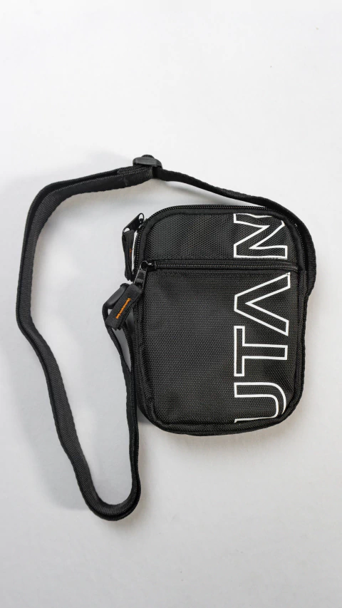 Bolsa shoulder bag preta Utan vista de cima, com alça ajustável e zíper frontal, ideal para acessórios e uso diário.