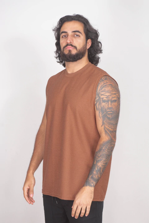 Homem vestindo regata machão Flush Castanho, peça sem mangas de cor marrom, ideal para o verão e looks casuais.