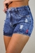 Close-up de shorts jeans feminino Nr13 com detalhes rasgados e etiqueta vermelha.