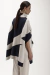 Mulher usando um colete jacquard maxi, com design em tons de azul e cinza, em um fundo neutro.