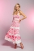 Modelo usando um top jacquard rosa com estampa de rosas, combinado com uma saia longa, em um fundo suave.