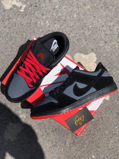 Desenvolvido com material em couro sua coloração predominante é o cinza com preto em suas laterais tem o símbolo da nike em preto, seu solado e vermelho com as linhas de costura preta o modelo acompanha 2 cadarços em preto é vermelho.
