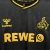 Detalhe da camisa terceira do 1. FC Köln temporada 2025-2026, com logos em amarelo sobre fundo preto e padrão geométrico sutil
