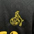 Logo bordado do 1. FC Köln em amarelo sobre camisa preta com padrão geométrico discreto