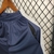 Short de futebol masculino da Umbro, cor azul, pendurado em um cabide.
