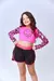 Menina sorridente usando um short de banho preto com detalhes em rosa e uma blusa rosa de manga longa com estampa divertida.
