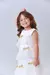 Menina sorridente usando um vestido branco com laços dourados e camadas de tule.