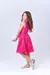 Menina sorridente usando um vestido de festa rosa com plumas, mostrando estilo e elegância.
