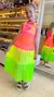Menina vestindo um vestido de praia infantil colorido, com camadas em neon rosa e verde, em uma loja de moda infantil.