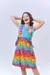 Menina sorridente usando um vestido de praia infantil colorido com estampa de girafa.