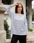 Mujer con camiseta de rayas blancas y negras, posando en un entorno urbano.