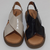 Sandalias MARGARITA ARENA de dos colores, una beige y otra negra, con diseño cruzado y suela cómoda.