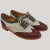Zapatos abotinados de cuero en tonos blanco, verde y marrón, con detalles de perforación y cordones.
