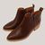 Botas cortas color chocolate de cuero con cierre lateral y suela clara sobre fondo blanco