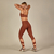 Calça Rafa com recorte moderno, exibida em ambiente fitness, destacando sua cintura alta e design inovador. Disponível nas cores preto e marrom.

