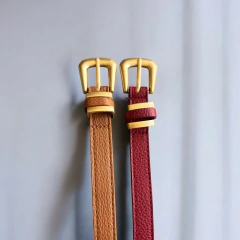 Cintos Zara com dois passantes e fivelas douradas, nas cores marrom e vinho, sobre fundo cinza claro.