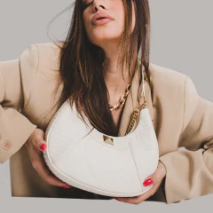 mulher sergurando um bolsa canoa em matelassê na cor branca com aplicações e corrente removível em dourado