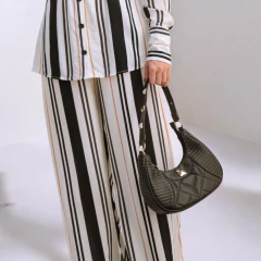 mulher segurando uma bolsa em matelassê na cor preta com aplicações e corrente removível em dourado