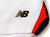 Detalhe da camisa São Paulo Home 25/26 da New Balance, mostrando o logo da marca em dourado e as cores do uniforme.