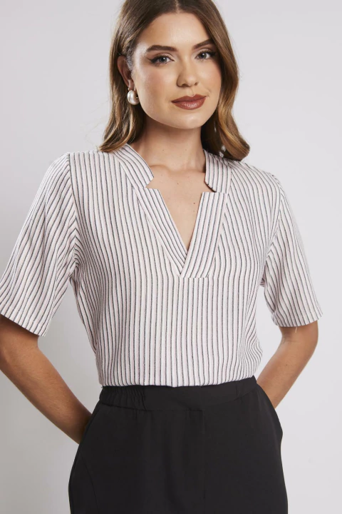 Mulher vestindo blusa listrada com gola V, manga curta e tecido leve, ideal para looks femininos casuais ou profissionais.