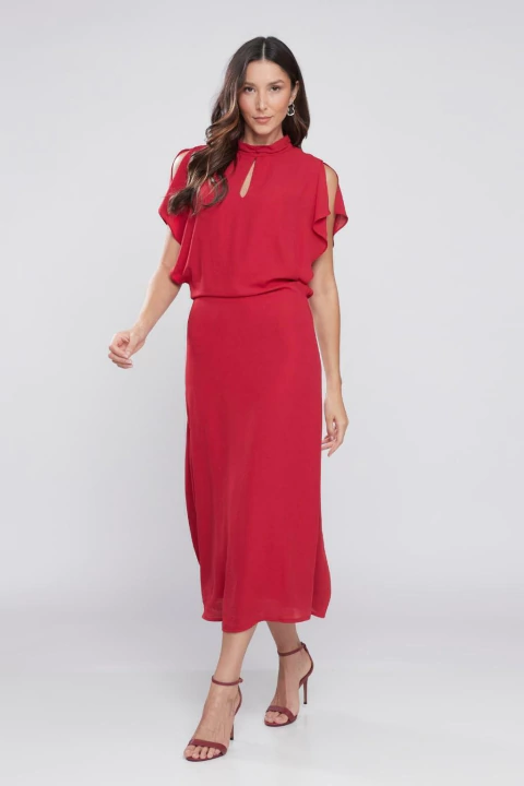 Modelo usando um vestido midi evasê na cor vinho com detalhes nos ombros.