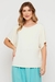 Modelo vestindo Blusa Tecno Ice Off White Rubinella, com decote canoa e mangas tipo kimono.